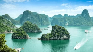 Bahía de Halong, Vietnam, con sus icónicas islas de piedra caliza cubiertas de vegetación y aguas esmeralda, con barcos navegando entre los islotes.