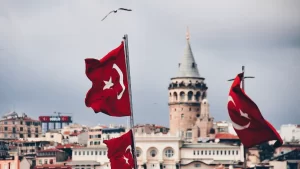 Banderas turcas ondeando frente a la Torre Gálata en Estambul, con una gaviota volando sobre el horizonte.